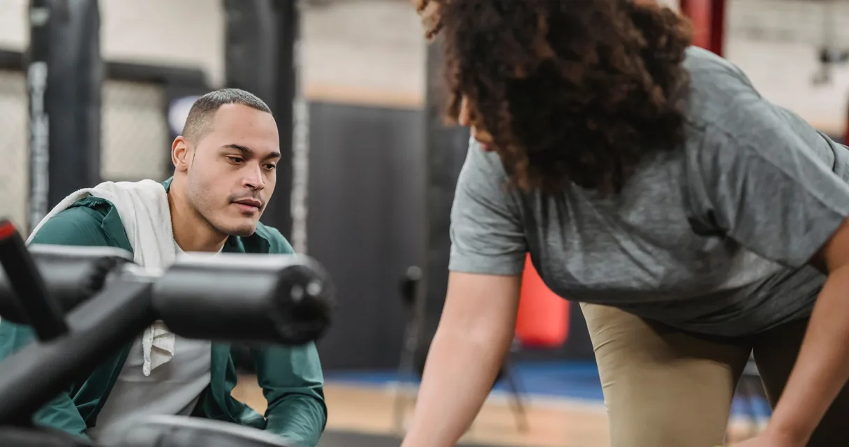 Personal trainer orientando uma aluna em exercício numa academia